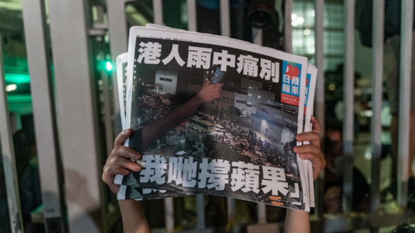 《苹果日报》在今年七一前被迫停刊。图为市民高举最后一期《苹果日报》以示支持。（图片来源：Getty Images）