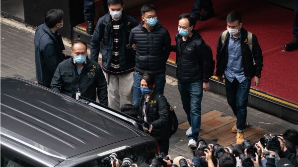 图为香港《立场新闻》的署理总编辑林绍桐（中）被国安警察带走。（图片来源：Getty Images）
