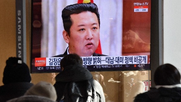 2022 年 1 月 1 日，人们在首尔火车站观看电视新闻节目，该节目正播出金正恩出席朝鲜劳动党中央委员会全体会议的照片