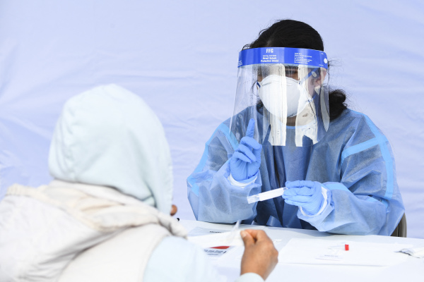 图为2022 年 1 月 18 日，美国加利福尼亚州霍桑市（Hawthorne）的一个新冠病毒快速检测点，一名医护人员在指导一位检测者如何用鼻拭子从鼻子中取样。（图片来源：PATRICK T. FALLON/AFP via Getty Images）