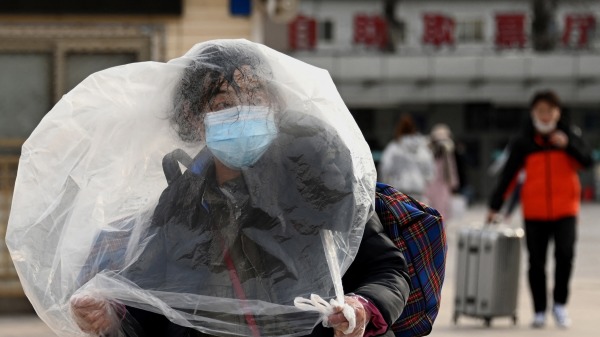 一名使用塑料袋作为掩护的妇女在北京火车站外行走