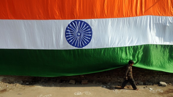 一个男孩跑过悬挂在孟买达拉维贫民窟狭窄通道之一的150多英尺长的手工制作的印度国旗。