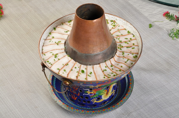 东北的火锅是以金属或陶瓷所制成的圆形锅，圆锅中间的烟筒则是要放置炭火用的。