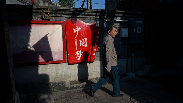 2022年10月6日北京，一名男子走过一幅中国梦的宣传标语牌。