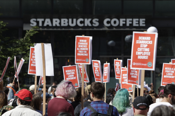 图为2022 年 4 月 23 日，在美国华盛顿州西雅图，星巴克公司总部所在地，有抗议人群在一家星巴克咖啡连锁店外举行“打击星巴克破坏工会”的集会和游行活动。（图片来源：JASON REDMOND/AFP via Getty Images）