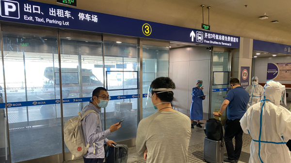 在北京国际机场，入境旅客正在等待被送往指定的隔离检疫场所