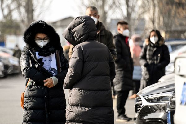 2022年12月20日，北京火葬场一名妇女举着亲人的相框。（图片来源：NOEL CELIS/AFP via Getty Images）