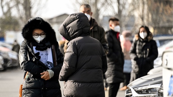 2022年12月20日，一名婦女在北京火葬場舉著親人的相框。