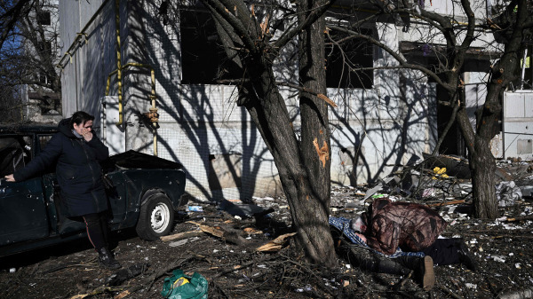 圖為2022 年 2 月 24 日，烏克蘭東部城鎮楚吉夫發生爆炸事件後，人們在被毀建築物外的親戚屍體旁哀悼