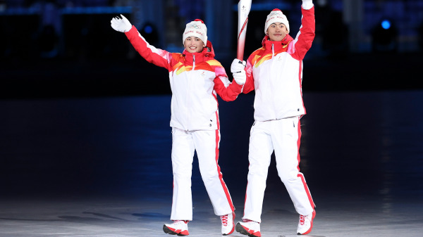 在中国北京国家体育场举行的北京2022年冬季奥运会开幕式上，火炬手维吾尔族运动员迪尼格尔．衣拉木江和汉族运动员赵嘉文举着奥运圣火