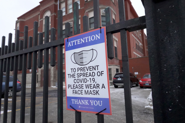 图为2022年1月5日，美国伊利诺伊州芝加哥市的一所小学的栅栏门上提醒学生、教职员工和访客戴口罩的标志。（图片来源：Scott Olson/Getty Images）