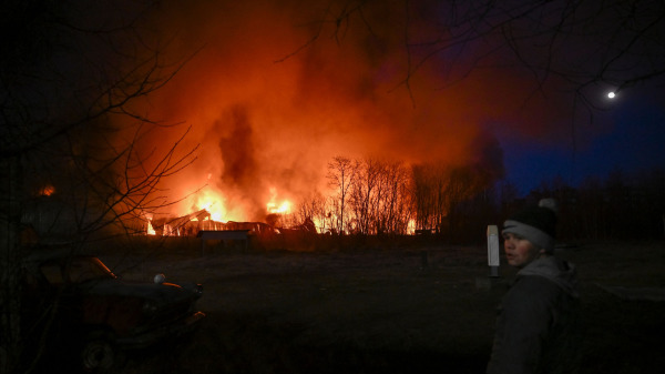 在乌克兰首都基辅遭到俄军炮击后，一个乌克兰男孩站在燃起大火的房屋前。