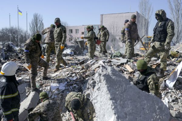 2022 年 3 月 19 日， 乌克兰南部港口城市尼古拉耶夫（Mykolaiv），乌克兰士兵在前一天被俄罗斯火箭弹击中的军事学校残骸中搜寻尸体。乌克兰媒体报导说，俄罗斯军队18日对Mykolaiv 进行了大规模空袭，造成至少 40 名乌克兰士兵阵亡。（图片来源：BULENT KILIC/AFP via Getty Images）