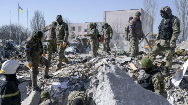 2022 年 3 月 19 日， 乌克兰南部港口城市尼古拉耶夫（Mykolaiv），乌克兰士兵在前一天被俄罗斯火箭弹击中的军事学校残骸中搜寻尸体。