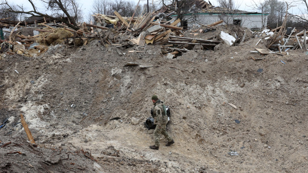 一名乌克兰军人在基辅地区北部前线的一个村庄检查俄罗斯导弹袭击造成的火山口。