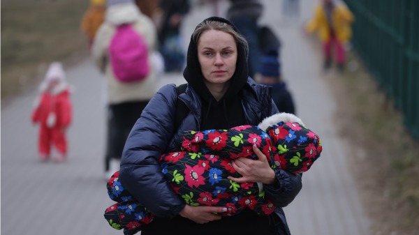 一名怀抱着婴儿的乌克兰母亲，逃离了遭受俄罗斯发动的侵略战争摧残的家园，抵达波兰避难。