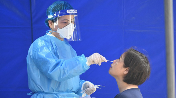 图为医护人员为一名女士做病毒检测。（图片来源：PETER PARKS/AFP via Getty Images）
