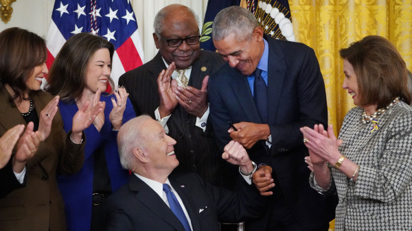 在華盛頓特區白宮東廳發表講話後，拜登（Biden，左三）簽署一項旨在加強平價醫療法案的行政命令，並與歐巴馬（Obama，右二）碰拳。現場還有賀錦麗和佩洛西。