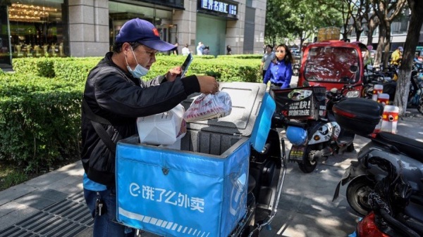 外卖人员在北京一条街道上检查食品订单，示意图。