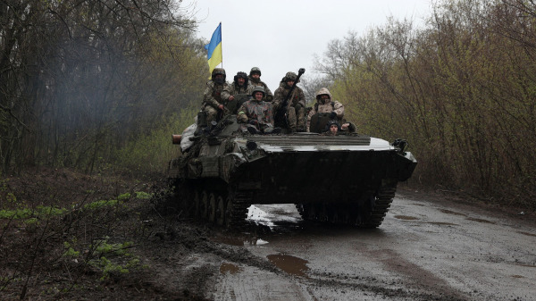 图为2022年4月18日，在距离俄罗斯军队不远的乌克兰哈尔科夫（Kharkiv）地区伊久姆（Izyum）前线，乌克兰士兵站在一辆装甲运兵车上（APC）