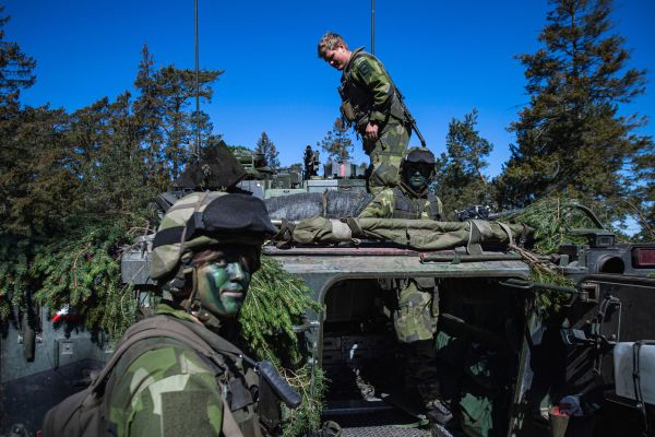 图为2022 年 5 月 17 日，瑞典陆军 P18 哥特兰团士兵在野战演习中伪装装甲车。（图片来源：JONATHAN NACKSTRAND/AFP via Getty Images）