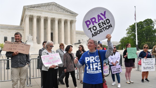 2022年5月4日，支持堕胎选择权的示威者站在一名反堕胎抗议者的身后，他们聚集在华盛顿特区的美国最高法院外。（图片来源：NICHOLAS KAMM/AFP via Getty Images)
