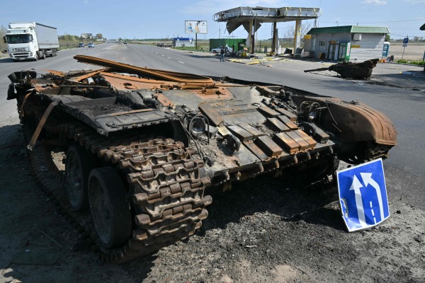 圖為2022 年 5 月 2 日，在烏克蘭首都基輔東北部的村莊斯凱賓（Skybyn），道路上還躺著一輛俄羅斯坦克的殘骸，對面是一個被戰火摧毀的加油站。這條路上的民用車輛從上週開始多了起來，人們開始返回繼續生活。俄羅斯軍隊從基輔地區撤離後，現在將主要兵力和火力集中在烏克蘭東部的頓巴斯（Donbas）地區。 （圖片來源：SERGEI SUPINSKY/AFP via Getty Images）