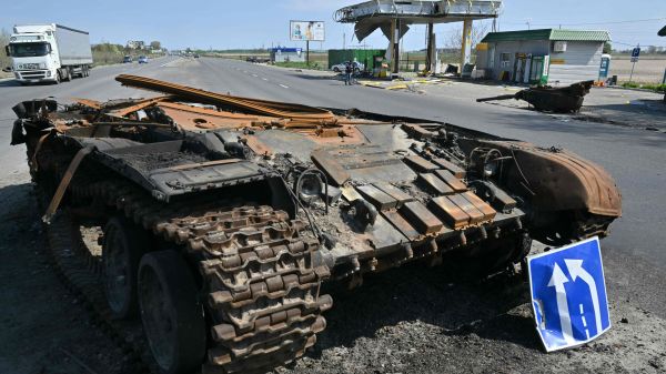 图为2022 年 5 月 2 日，在乌克兰首都基辅东北部的村庄斯凯宾（Skybyn），道路上还躺着一辆俄罗斯坦克的残骸，对面是一个被战火摧毁的加油站。