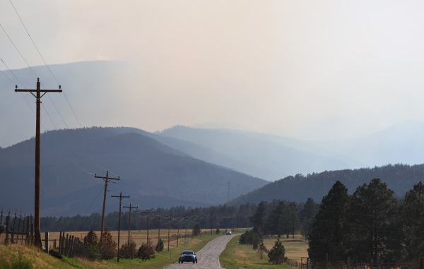 图为2022 年 6 月 2 日，美国新墨西哥州的拉斯维加斯附近，隐士峰/小牛峡谷（Hermits Peak/Calf Canyon）上的山火还在燃烧。新墨西哥州的山火已经燃烧了两个月，过火面积超过500 平方英里（1,300 平方公里），上面的 430 多所房屋被烧毁。已经追踪到的两起山火来源是联邦森林管理部门作为预防而实施的放火烧林措施失控所致。（图片来源：Mario Tama/Getty Images）