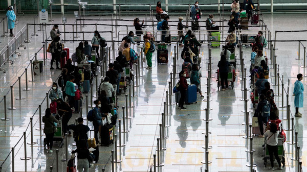 图为入境人士在香港国际机场排队等候前往酒店隔离检疫。