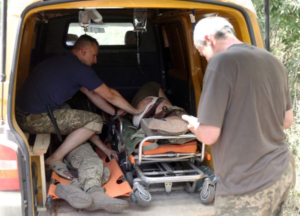 图为2022 年 6 月 21 日， 在乌克兰东部顿巴斯地区的一条道路上，一名乌克兰军人在照顾他的两名受伤的战友乘坐简易救护车撤离前线。（图片来源：ANATOLII STEPANOV/AFP via Getty Images）