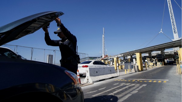2019年10月2日，一名美国海关和边境保护局人员在加州圣伊西德罗的入境口岸检查一辆汽车是否有违禁品进入美国。（SANDY HUFFAKER/AFP via Getty Images)