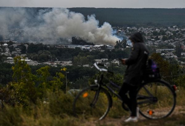 圖為 2022 年 9 月 11 日拍攝的照片，一個騎自行車的人停在能夠俯瞰烏克蘭東部哈爾科夫（Kharkiv）地區重鎮伊久姆（Izyum）的小山上，山下還冒著戰火。烏克蘭軍隊表示，他們的閃電戰反攻在過去三天時間裡奪回了哈爾科夫地區的幾乎所有領土。這一天標誌著俄烏戰爭的第200天，也是烏克蘭對俄羅斯入侵和佔領的最大逆轉。（圖片來源：JUAN BARRETO/AFP via Getty Images）