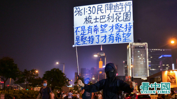 图为反送中期间，一位年轻人自发在街头举牌，呼吁市民参加民阵游行。（摄影：庞大卫/看中国）