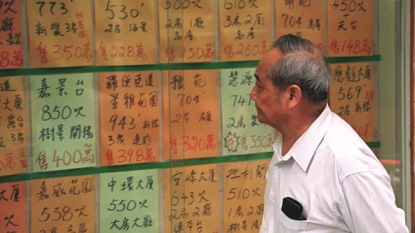 一名男子在香港房地產經紀人的櫥窗裡閱讀出售住宅物業的廣告。