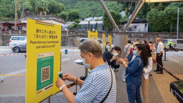 香港赛马场门口一位民众在扫描香港政府的“安全离家”应用程序的二维码。