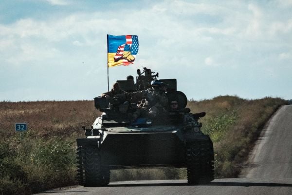 图为2022 年 9 月 19 日，一辆乌克兰坦克在哈尔科夫（Kharkiv）地区的新斯特帕尼夫卡（Novostepanivka）的公路上行驶，坦克上高高飘扬着一面显示乌克兰国旗和美国国旗握手的旗帜。在美国的武器和情报支持下，乌克兰于9月初发动的大反攻把其东北部的哈尔科夫地区从俄罗斯军队手中夺了回来。（图片来源：YASUYOSHI CHIBA/AFP via Getty Images）