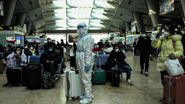 2022年12月28日，北京一處火車站中，一位乘客穿著全身防護服。