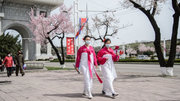在這張拍攝於2022年4月13日的照片中，行人走過平壤凱旋門附近的櫻花樹。