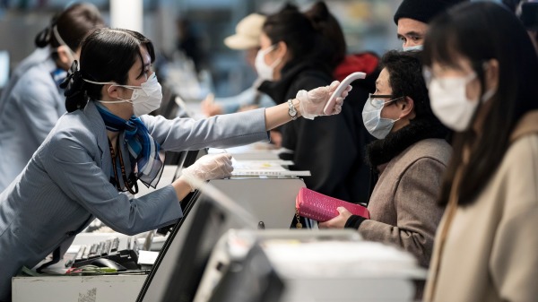 2020年1月30日，日本東京羽田機場，一名工作人員在測量旅客體溫。（Tomohiro Ohsumi/Getty Images）(16:9)