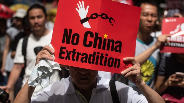 2019 年 6 月 9 日，在香港反送中集會期間，一名抗議者舉著標語牌遊行