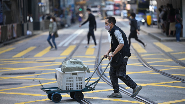 《国安法》实施三年半，香港退化成为“国际金融中心遗址”，不少港人失业。图为一名送货员正在过马路。（图片来源：Getty Images）