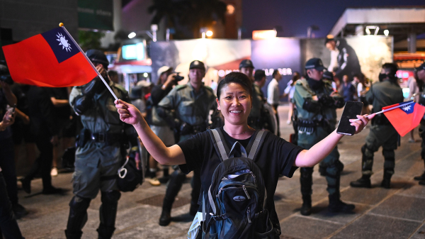 圖為2019年10月10日，一名抗爭者在警員面前舉起台灣國旗慶祝雙十節。（圖片來源：Getty Images）