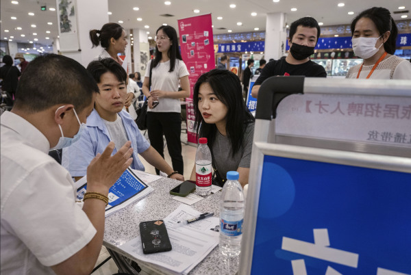 2023年6月9日，中國北京的招聘會上，一對年輕男女在求職時與招聘人員交談。