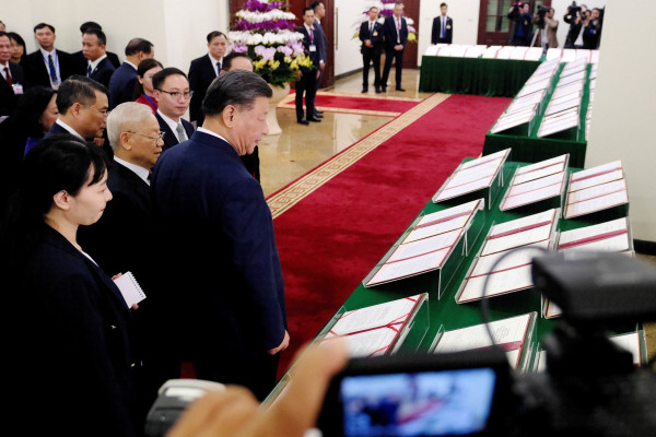 2023年12月12日，中國國家主席習近平和越南共產黨總書記阮富仲（中左）走過河內越南共產黨中央辦公廳展示的簽署協議。