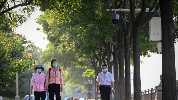 2022年9月27日的照片显示，人们走过北京一条道路上的闭路电视 (CCTV) 监视器（JADE GAO/AFP via Getty Images)(