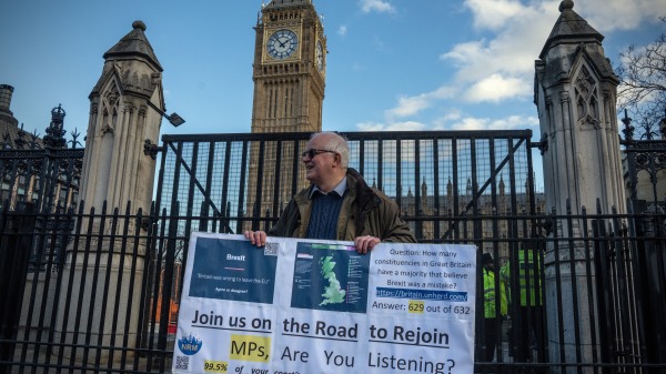 2023年1月31日是英国脱欧3周年，一名活动人士在伦敦国会大厦外举着反对英国脱欧的标语牌。