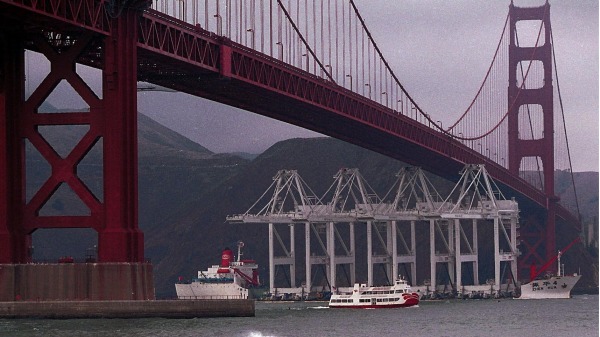 2000年10月24日，四台世界上最大的起重机在美国旧金山金门大桥下方，这四部机器均由中国上海振华港机公司制造，高220 英尺（66 米）高。这些起重机的目的地是加利福尼亚州的奥克兰港。（图片来源：JOHN G. MABANGLO/AFP via Getty Images）(16:9)