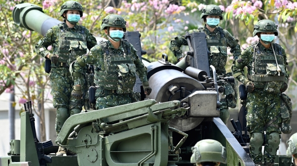 2020 年 4 月 9 日，在台灣總統蔡英文訪問台灣南部台南的一個軍事基地期間，在 COVID-19 冠狀病毒大流行期間戴著口罩的女兵站在美國製造的 M110A2 自行榴彈砲上。