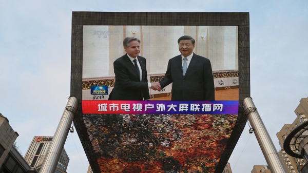 2023 年 6 月 19 日，中国中央电视台的新闻广播在北京一家购物中心外的大屏幕上播放了美国国务卿安东尼・布林肯（左）会见中国国家主席习近平的镜头。